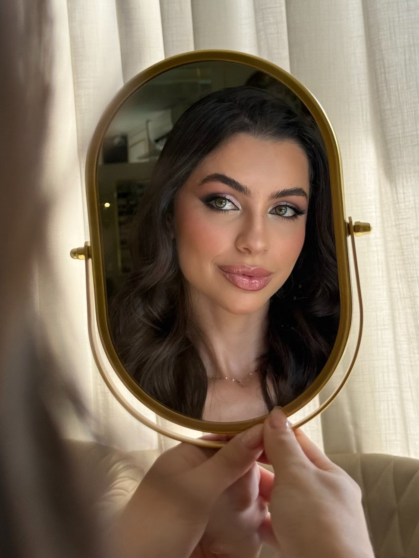 Maquiagem em tons de rosa refletida em um espelho de mesa dourado